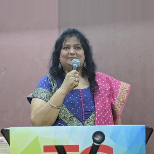Mallikaa speaking on stage with a microphone
